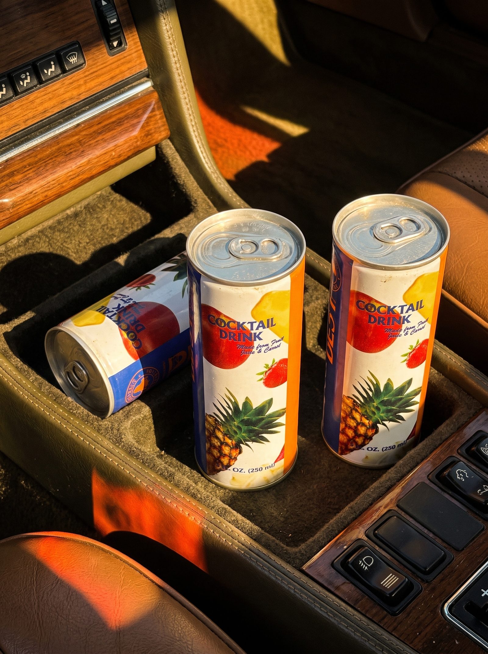 Three BEST Cocktail Drink tins in the console of a classic car in golden light